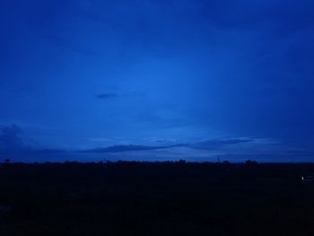 Silhouette landscape against blue sky at night
