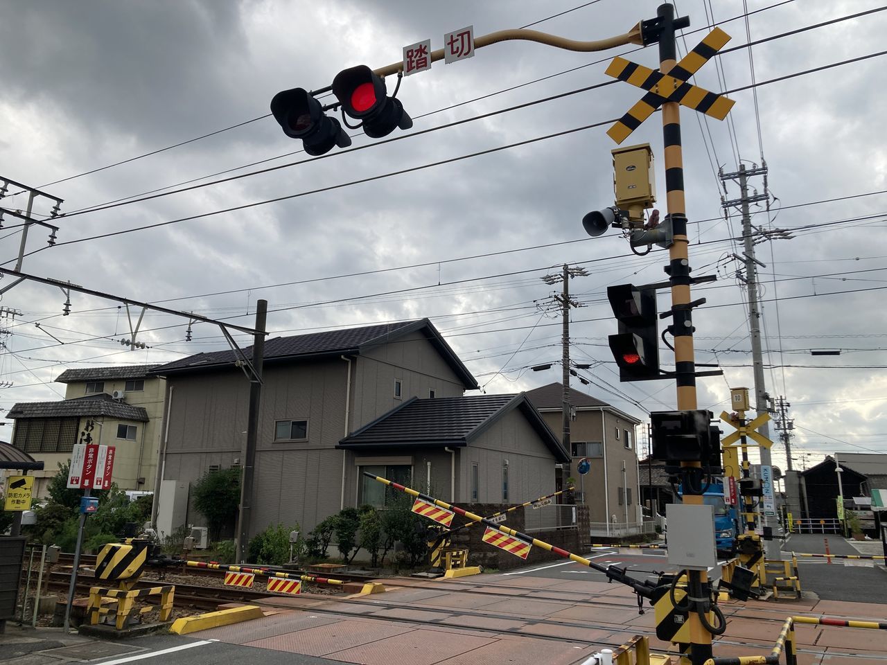 cable, cloud, architecture, sky, electricity, traffic light, sign, city, signaling device, street, transportation, building exterior, built structure, road, power line, light, technology, stoplight, nature, transport, urban area, red light, mode of transportation, communication, day, lighting, outdoors, electricity pylon, road signal, power supply, road sign