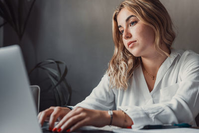 Young woman using laptop while sitting in office