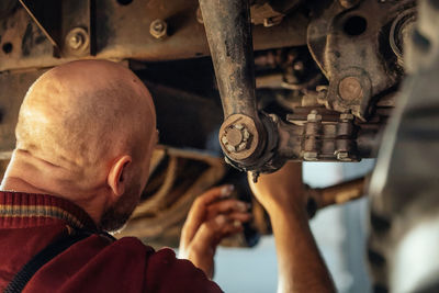 Rear view of mechanic repairing car in auto repair shop