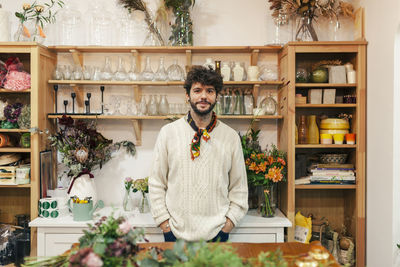 Smiling craftsman with hands in pockets at floral shop