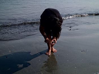 Woman standing on wet shore at beach