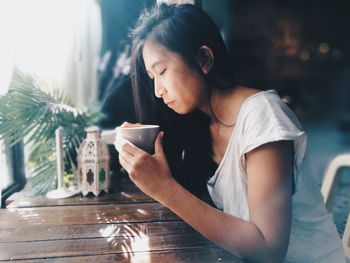 Young woman sitting on table at home