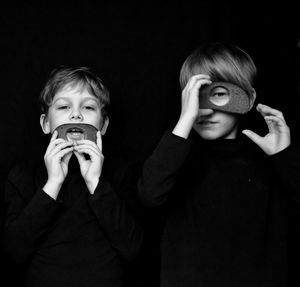 Portrait of siblings holding breads against black background