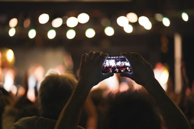 Midsection of woman photographing illuminated mobile phone at night