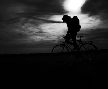 Silhouette man with bicycle against sky during sunset