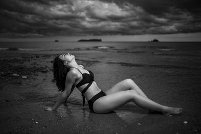 Woman on beach by sea against sky