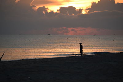 Silhouette person standing on beach against sky during sunset