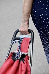 Low section of woman holding shopping cart on street in city