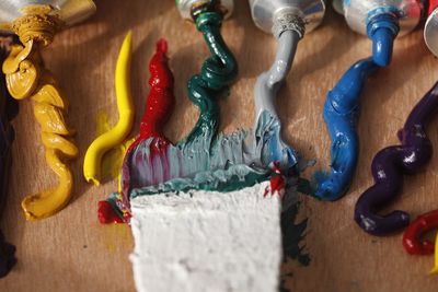 High angle view of colorful paints with brush on table at workshop