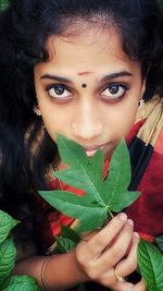 Portrait of young woman holding leaves