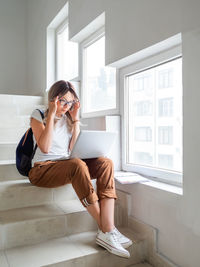 Side view of young woman using mobile phone at home