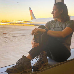 Man looking at camera while sitting on airport runway against sky