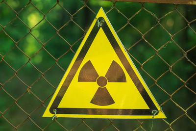 Close-up of yellow sign on chainlink fence