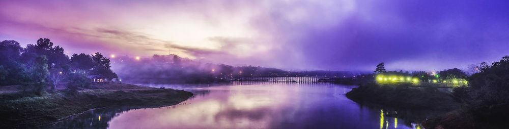 Scenic view of lake against cloudy sky at dusk