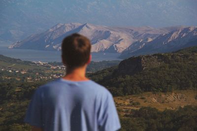 Rear view of man looking at mountains against sky