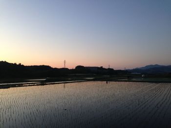 Scenic view of lake against clear sky during sunset