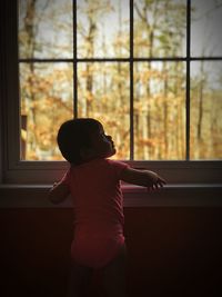 Girl looking through window at home