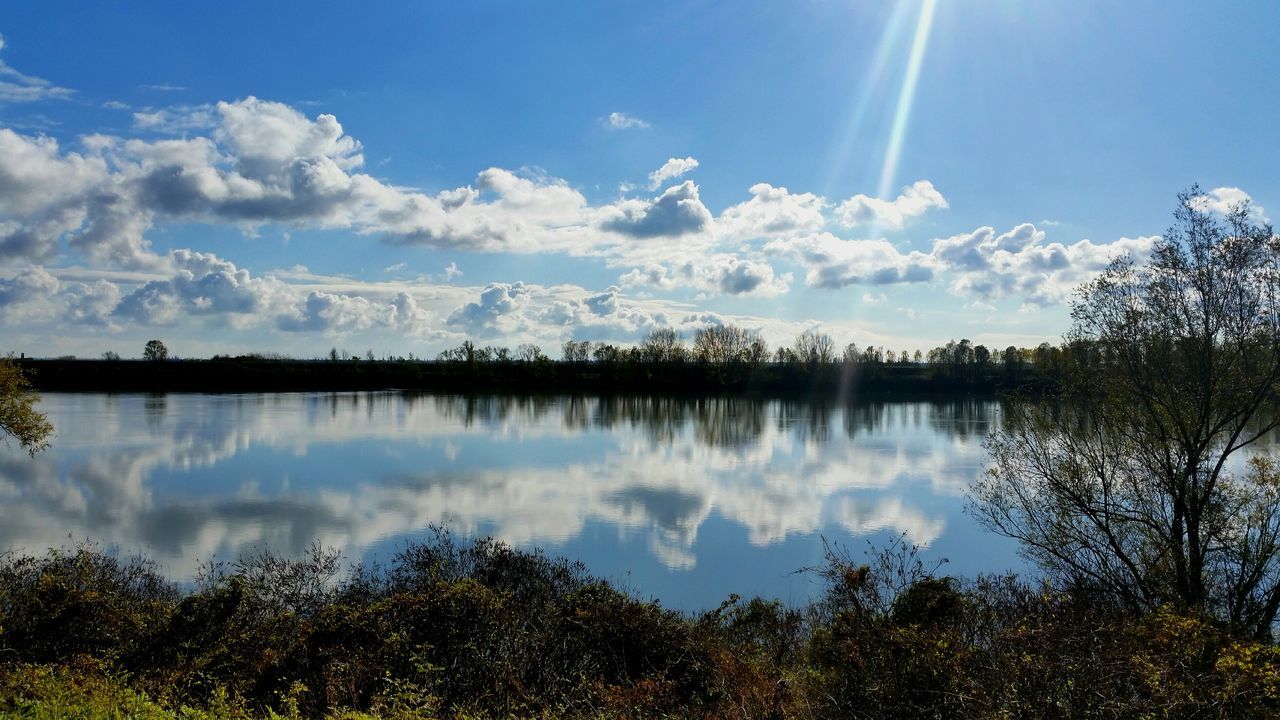 tranquil scene, tranquility, sky, reflection, scenics, lake, beauty in nature, water, tree, nature, sunlight, sunbeam, cloud - sky, blue, sun, idyllic, cloud, grass, growth, outdoors