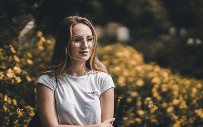 Close-up of beautiful woman standing against yellow flowers