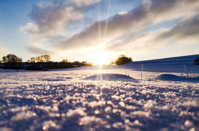 Scenic view of snow covered land against sky during sunset