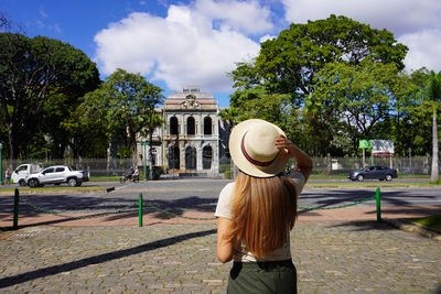 Rear view of woman standing against trees