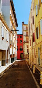 Empty road amidst buildings against sky