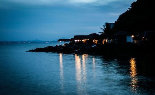 Scenic view of sea and silhouette buildings against sky at dusk