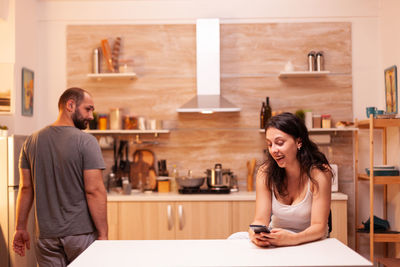 Portrait of young woman using mobile phone while sitting on table