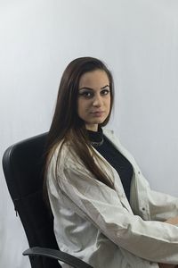 Portrait of woman sitting on chair against wall