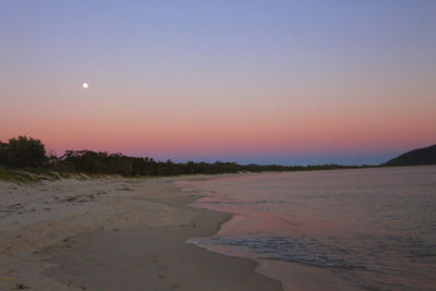 Scenic view of beach against clear sky during sunset