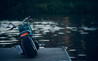 Motorcycle parked on pier by lake