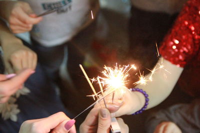 Midsection of woman holding sparkler at night