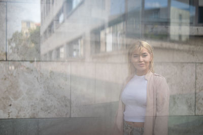 Double exposure of beautiful young woman standing in front of building