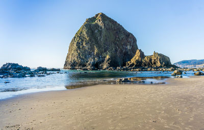 Panoramic shot of rocks on beach against clear blue sky