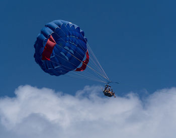 Low angle view of person parasailing against blue sky