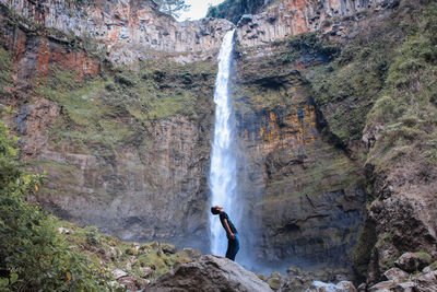 Optical illusion of man drinking waterfall