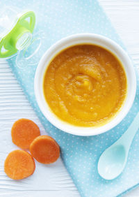 Baby carrot mashed with spoon in bowl, baby food