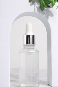 Beauty collagen face oil in a glass dropper bottle in arch. trendy shoot of cosmetics packaging.