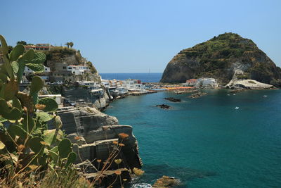 Panoramic view of sea and rocks against clear blue sky