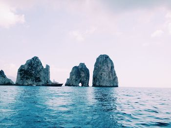 Stack rocks in sea against cloudy sky