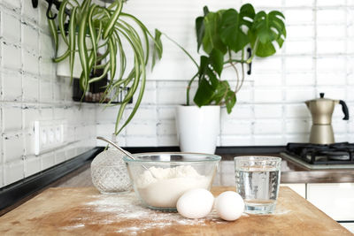 Pouring water into flour. making dough  in  kitchen in scandinavian stile. eggs, flour and water