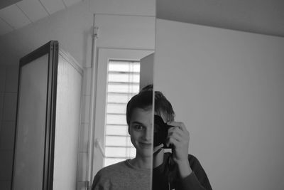 Young woman looking away while standing on mirror