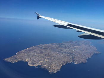 Airplane flying over sea against blue sky