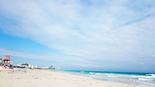 Distant view of buildings by sea against sky