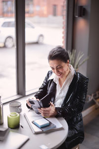 Mature woman using cell phone in cafe