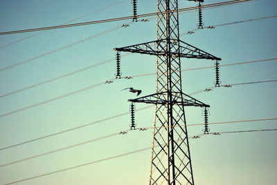 Low angle view of electricity pylon against clear sky