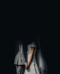 Rear view of women standing against black background