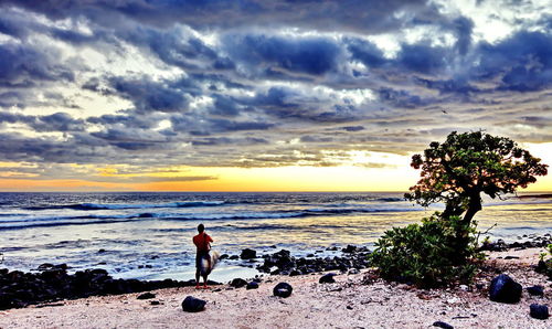 People standing on beach against sky during sunset