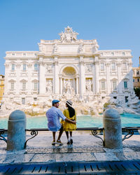 Full length rear view of people walking against blue sky